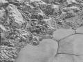 V tomto obrázku s nejvyšším rozlišením jsou zobrazeny velké kusy kůry z vodního ledu, napěchované v pohoří al-Idrisi. Některé strany hor se zdají být potažené tmavým materiálem, zatímco ostatní jsou světlé. Několik příkrých stěn vykazuje vrstvení kůry, snad související s vrstvami viditelnými v kráterech. Další materiál je zřejmě drcený mezi horami, jako by tyto velké bloky vodního ledu, některé vysoké 2,5 km, byly strkány sem a tam. Pohoří náhle končí na pobřeží u planiny Sputnik, kde jsou měkké, na dusík bohaté ledové pláně tvořící téměř rovný povrch, přerušovaný pouze jemnými stopami výrazných hranic buničitých oblastí se strukturovaným povrchem (to patrně souvisí se sublimací způsobenou slunečním zářením). Obrázek zobrazuje krajinu 80 km širokou. Nahoře je severozápad
